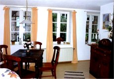 Wohnbereich Gustav mit Tisch und Stuehlen im besonderen Ambiente, Blick auf den Innenhof